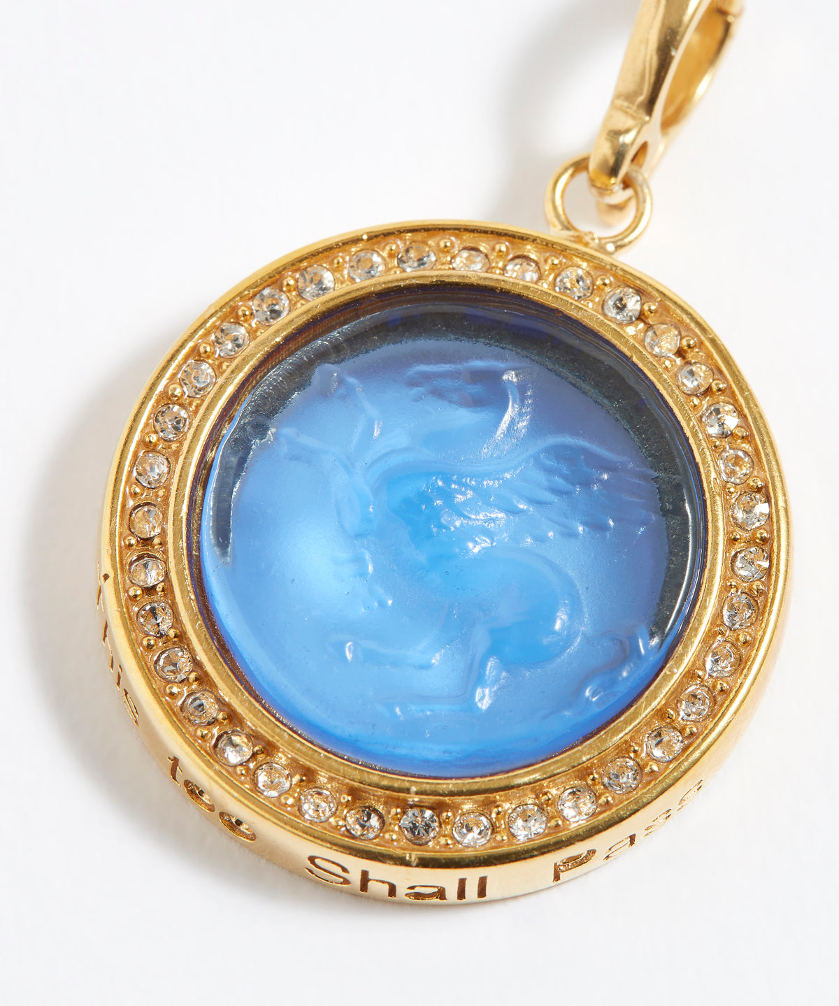 Gold pendant with blue central stone and "this too shall pass" engraving on a white background