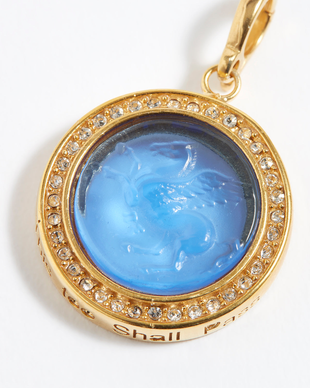 Gold pendant with blue central stone and "this too shall pass" engraving on a white background