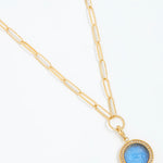 Gold chain necklace with a blue pendant on a white background