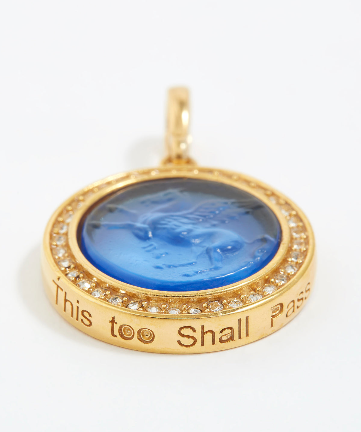 Gold pendant with blue center and engraved text "this too shall pass" on a white background