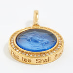 Gold pendant with blue center and engraved text "this too shall pass" on a white background