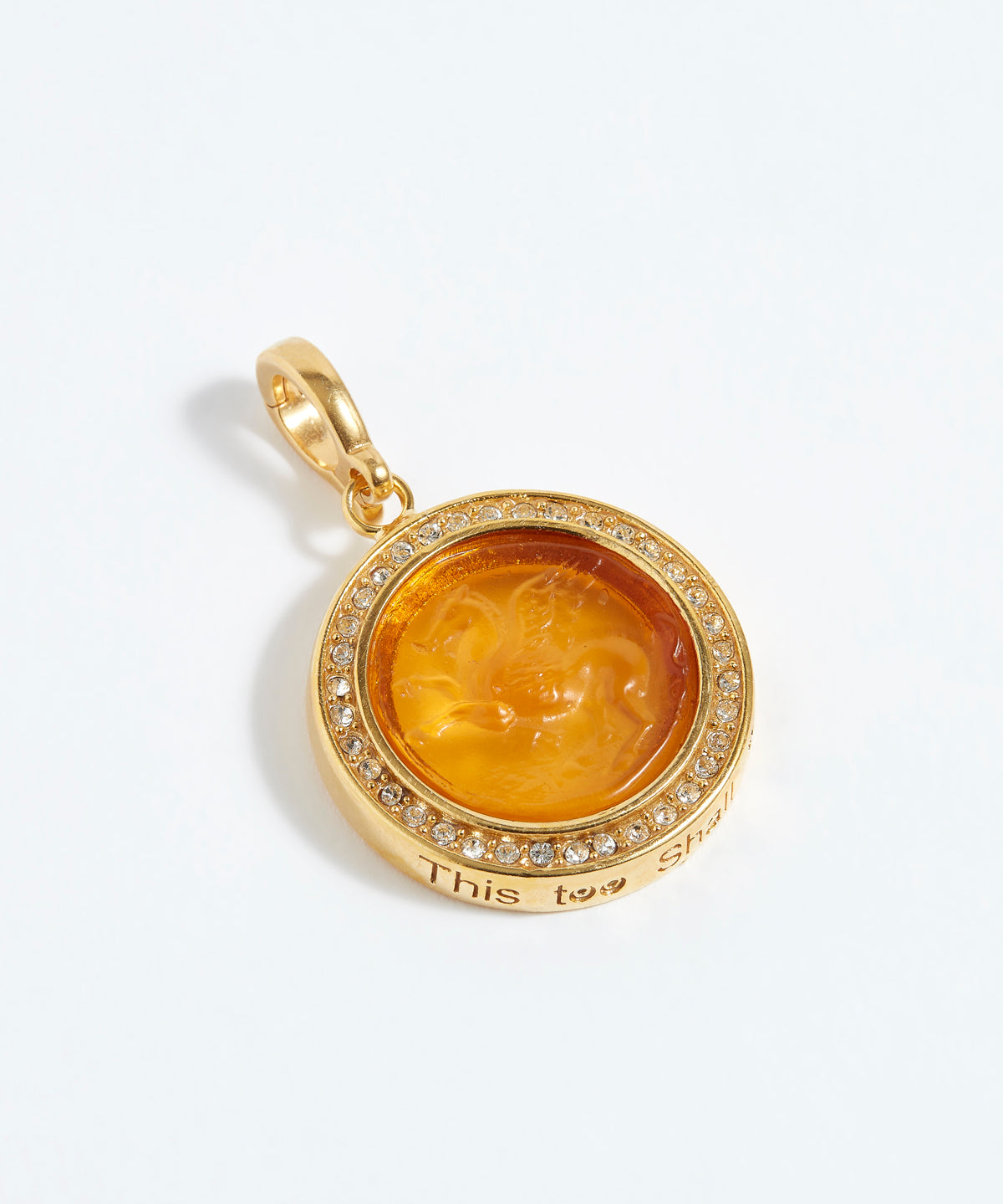 Gold pendant with a face design and "this too shall pass"  engraving on a white background