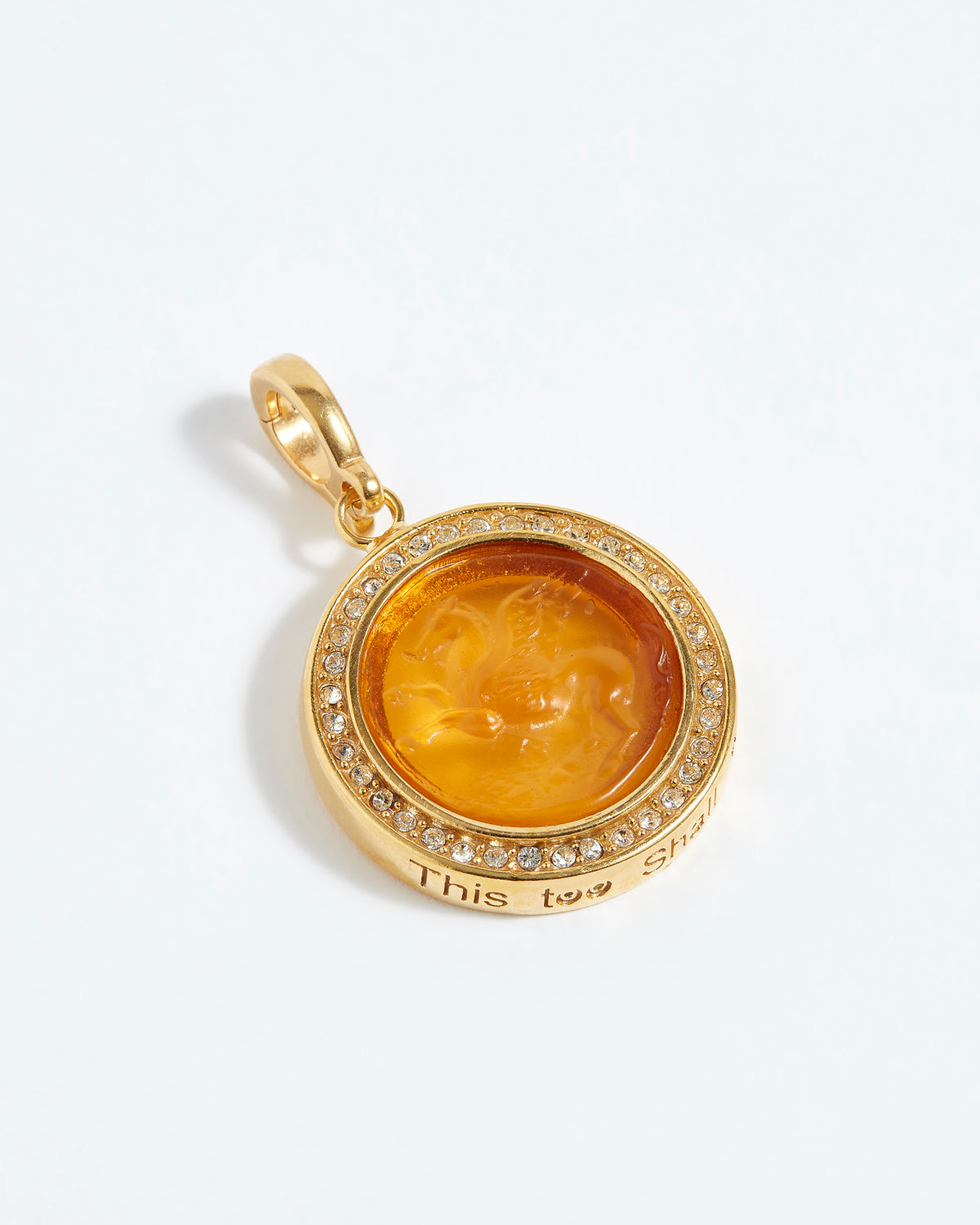Gold pendant with a face design and "this too shall pass"  engraving on a white background