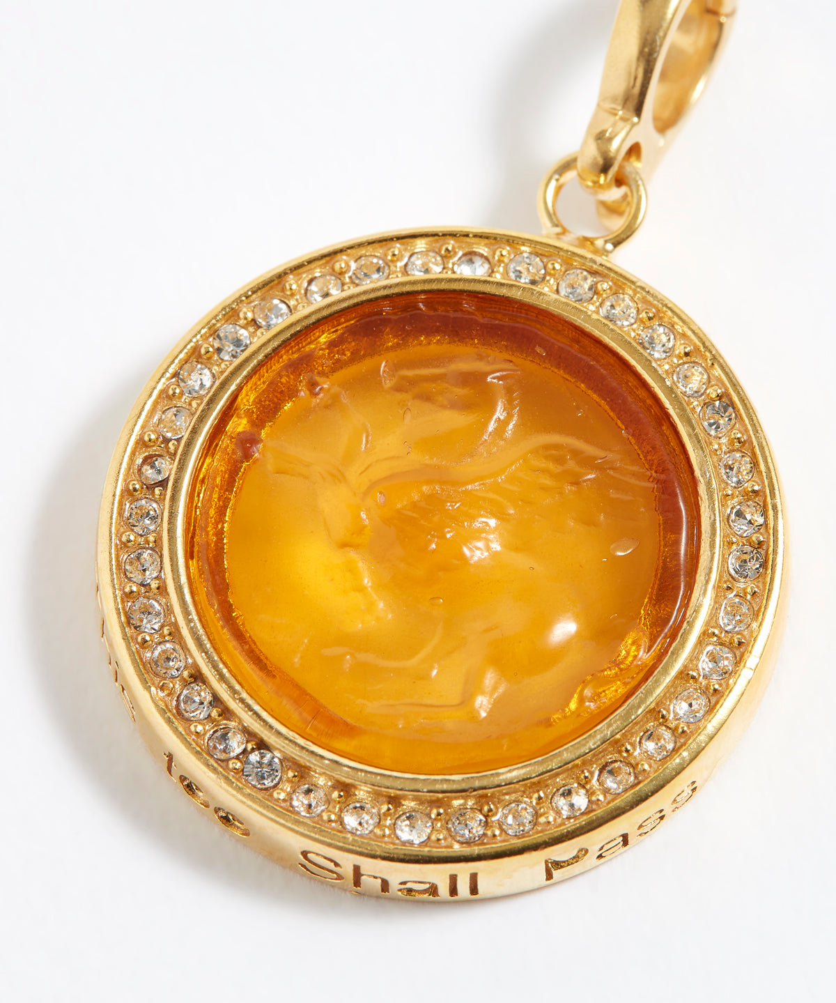 Gold pendant with a yellow center and embedded crystals on a white background
