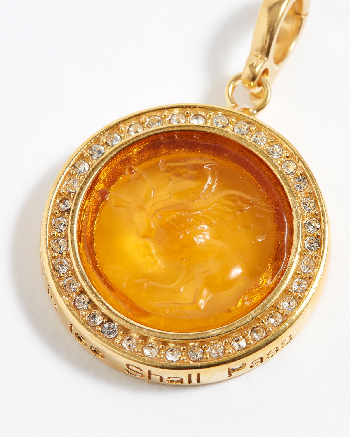 Gold pendant with a yellow center and embedded crystals on a white background