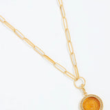 Gold necklace with a round pendant on a white background