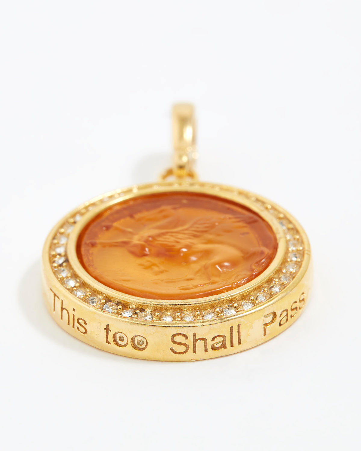 Gold pendant with engraved text "this too shall pass" on a white background