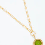 Gold necklace with a green pendant on a white background