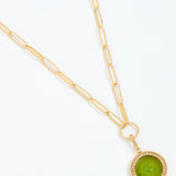 Gold necklace with a green pendant on a white background
