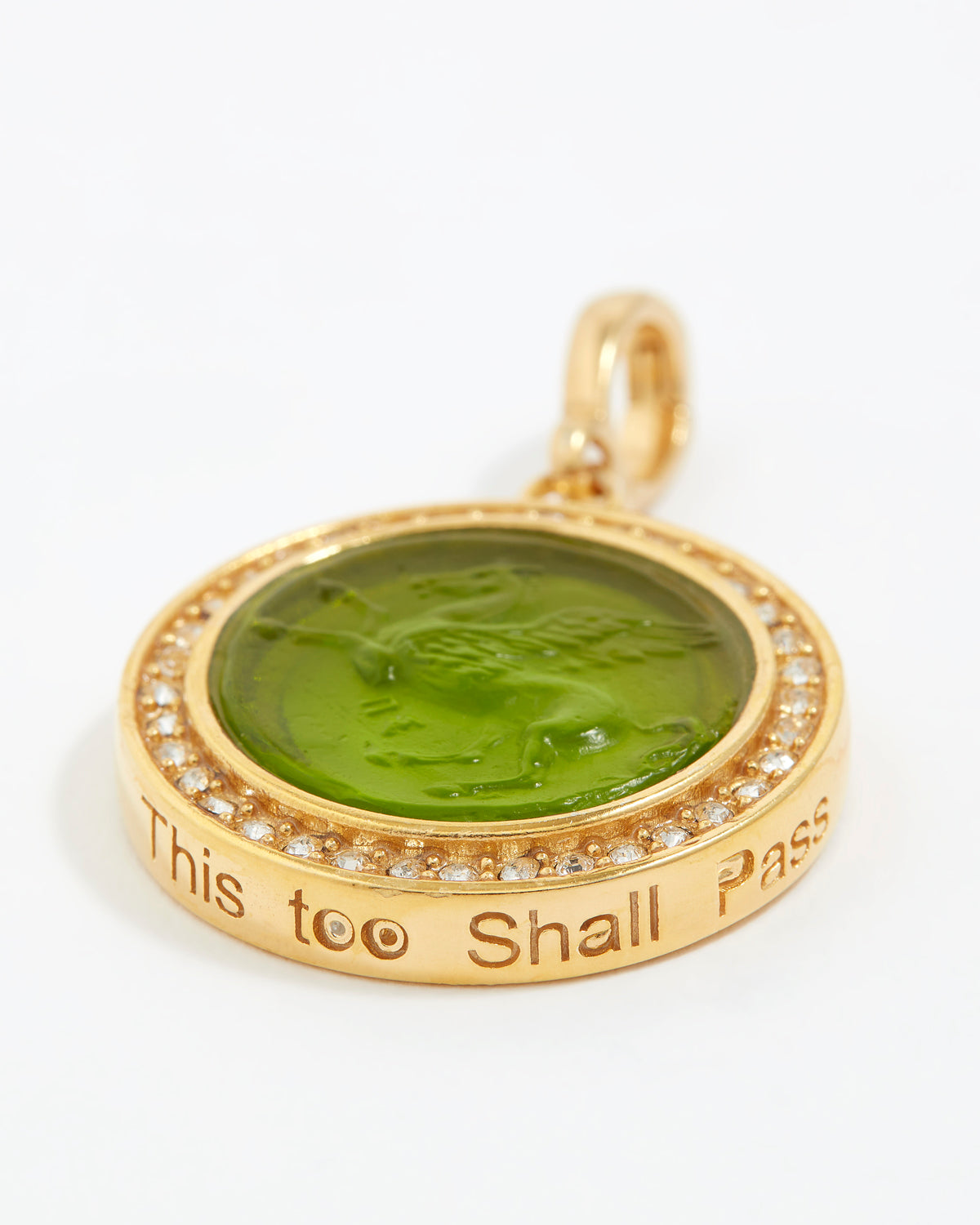 Gold pendant with green stone and engraved text "this too shall pass"  on a white background