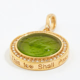 Gold pendant with green stone and engraved text "this too shall pass"  on a white background