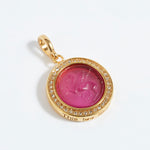 Gold pendant with pink gemstone and engraved text "this too shall pass" on a white background