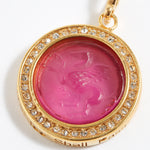 Gold pendant with pink gemstone and engraved text "this too shall pass"  on a white background