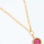 Gold necklace with a pink gemstone pendant on a white background