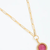 Gold necklace with a pink gemstone pendant on a white background