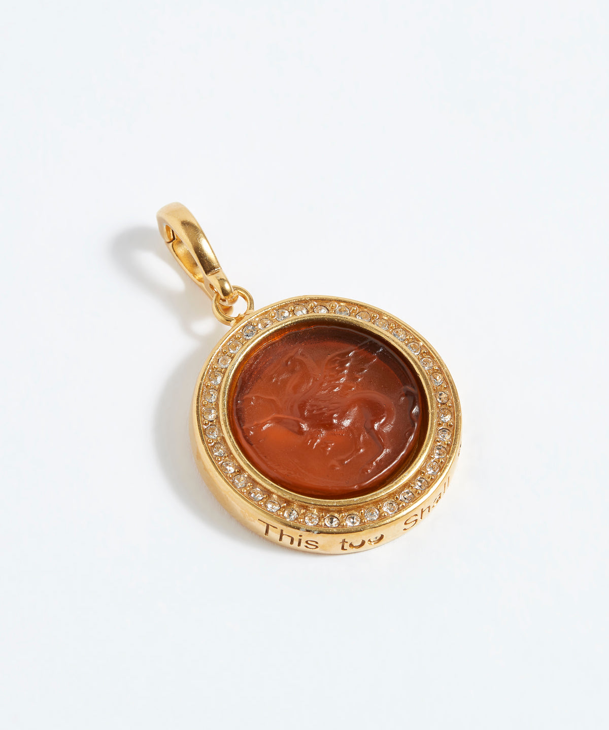 Gold pendant with a circular design and embedded stone on a white background