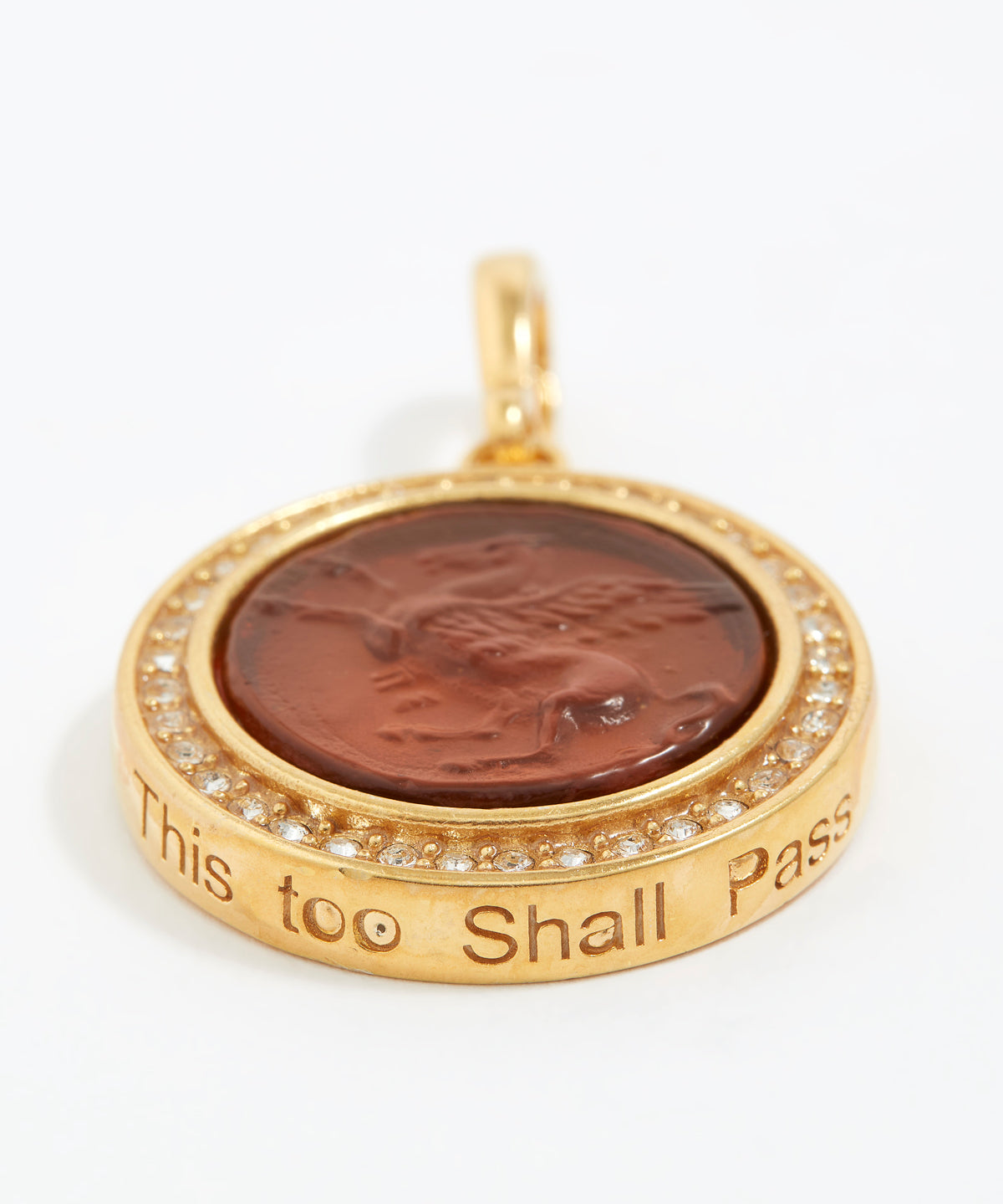 Gold pendant with a brown central stone and engraved text  "this too shall pass" on a white background