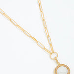 Gold necklace with a circular pendant on a white background