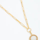 Gold necklace with a circular pendant on a white background