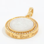Gold pendant with white stone and engraved text "this too shall pass" on a white background