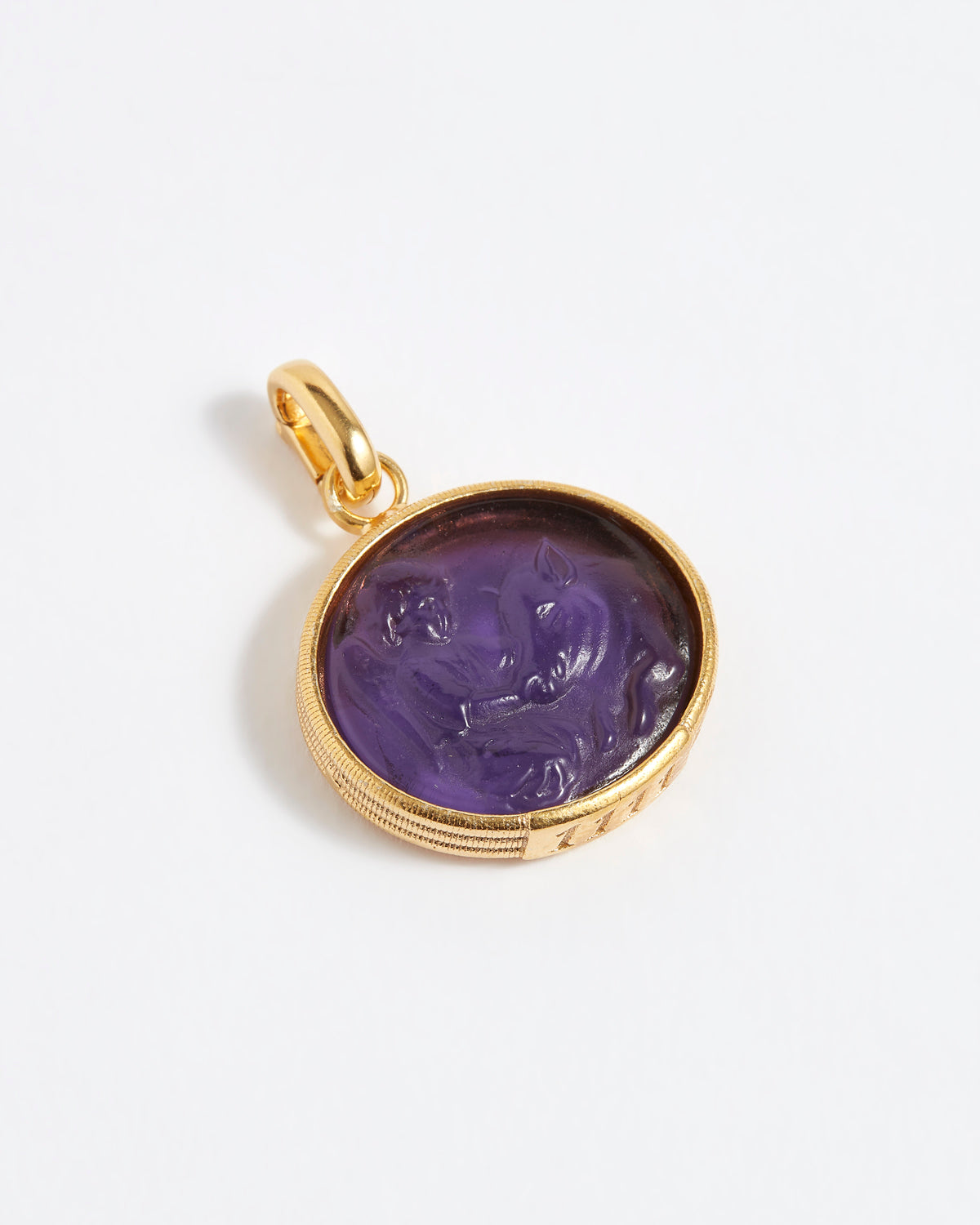 Gold pendant with a purple stone on a white background