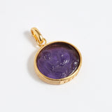 Gold pendant with a purple stone on a white background