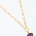 Gold necklace with a purple pendant on a white background