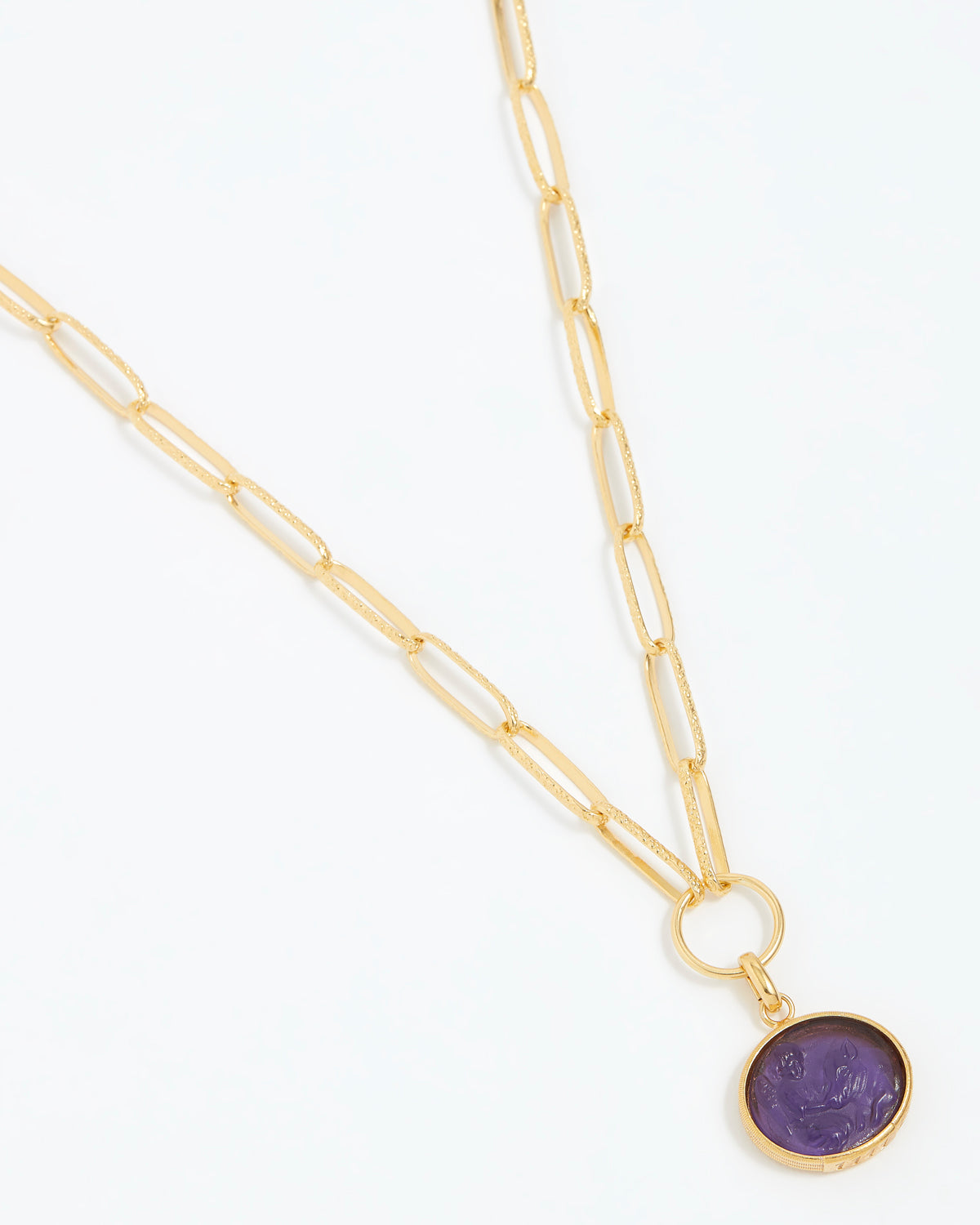 Gold necklace with a purple pendant on a white background