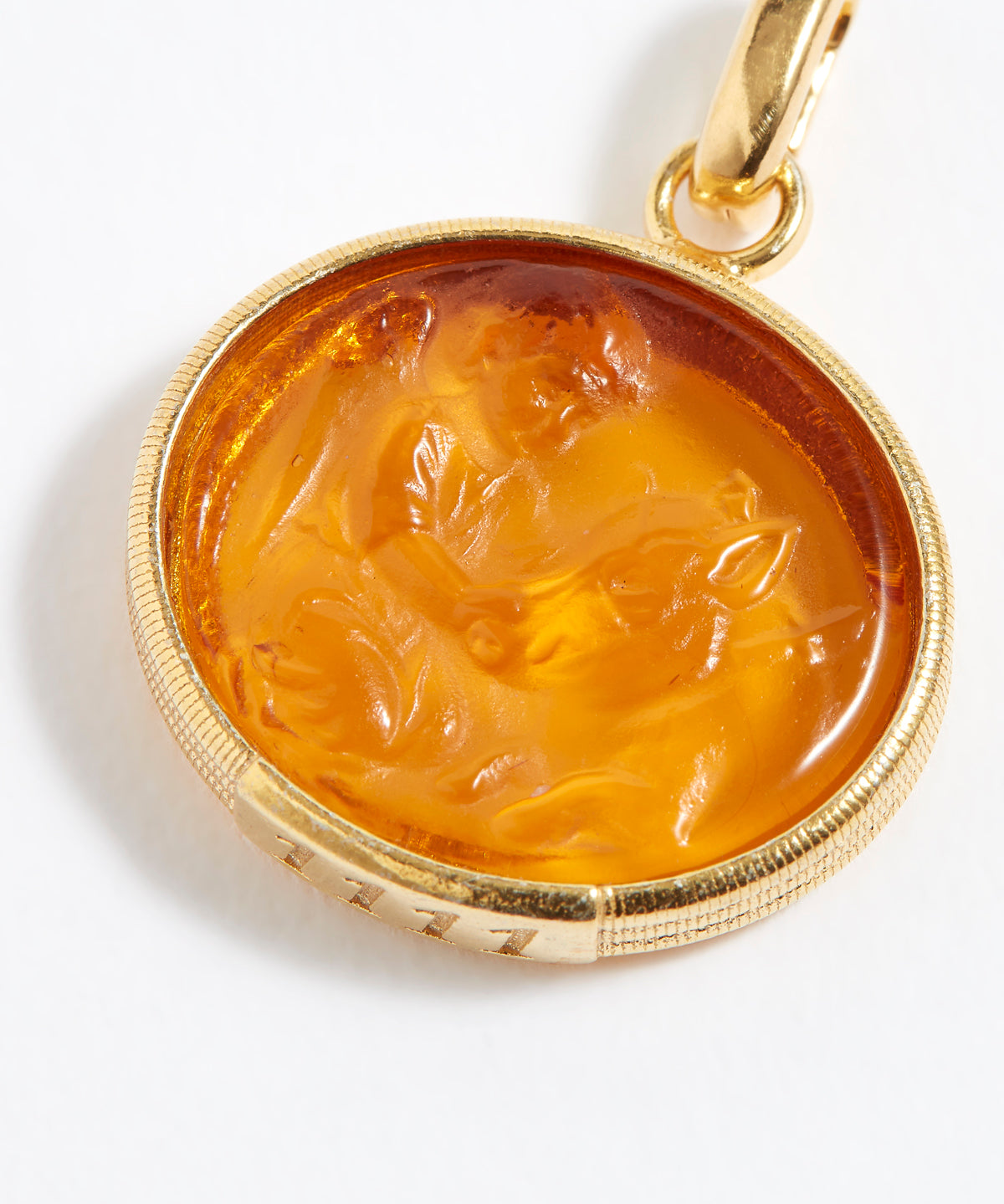 Gold pendant with a carved topaz stone on a white background