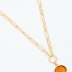 Gold necklace with a circular pendant on a white background