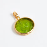 Gold pendant with a green stone on a white background