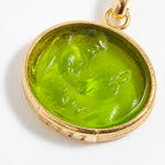 Gold pendant with a green stone on a white background