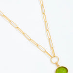 Gold necklace with a green pendant on a white background