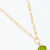 Gold necklace with a green pendant on a white background