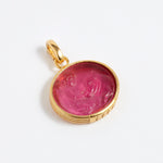 Gold pendant with a pink stone on a white background