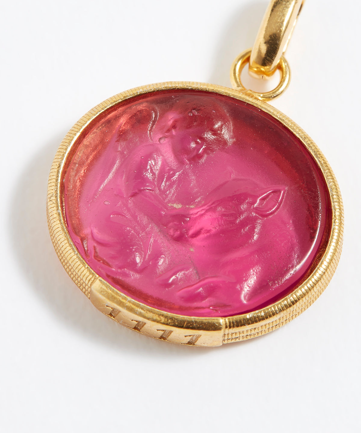 Gold pendant with a pink stone featuring a engraved design on a white background