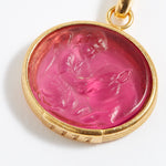 Gold pendant with a pink stone featuring a engraved design on a white background