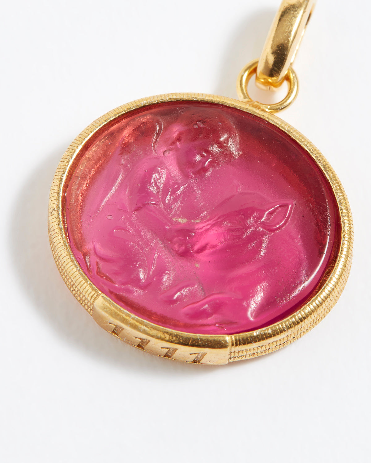 Gold pendant with a pink stone featuring a engraved design on a white background