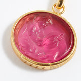 Gold pendant with a pink stone featuring a engraved design on a white background