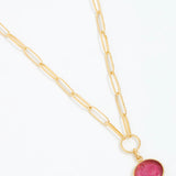 Gold necklace with a pink pendant on a white background