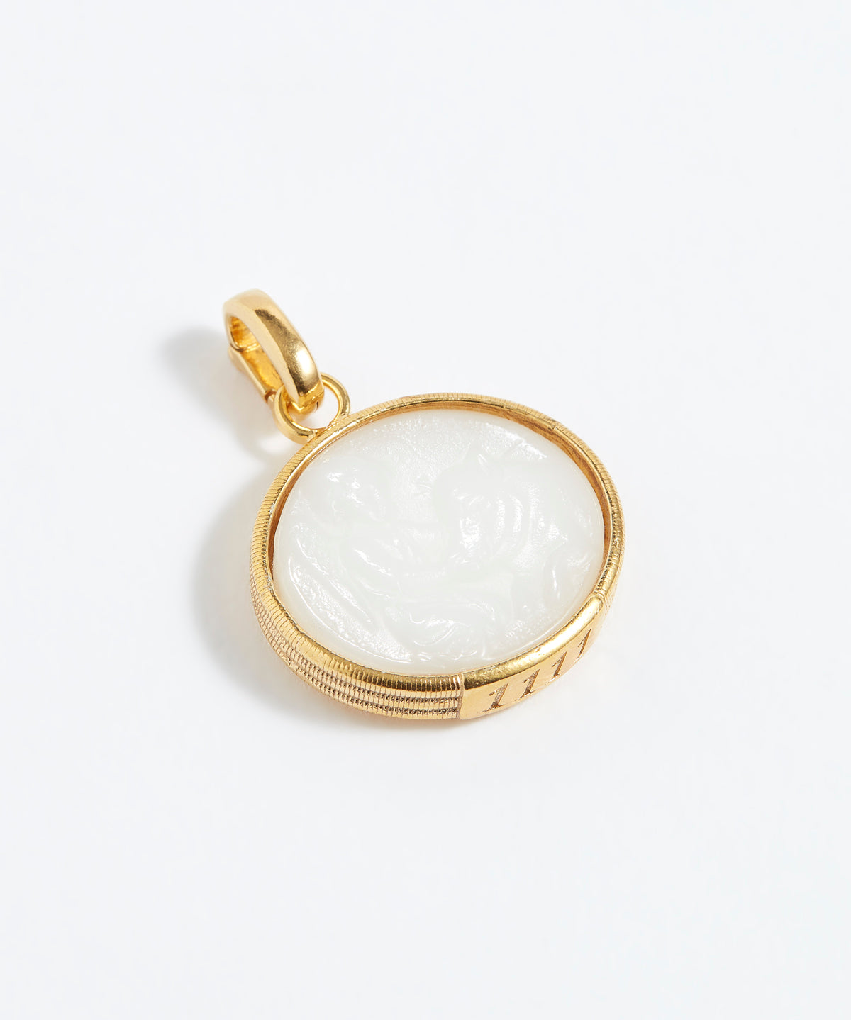 Gold pendant with a white stone on a light gray background