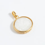 Gold pendant with a white stone on a light gray background