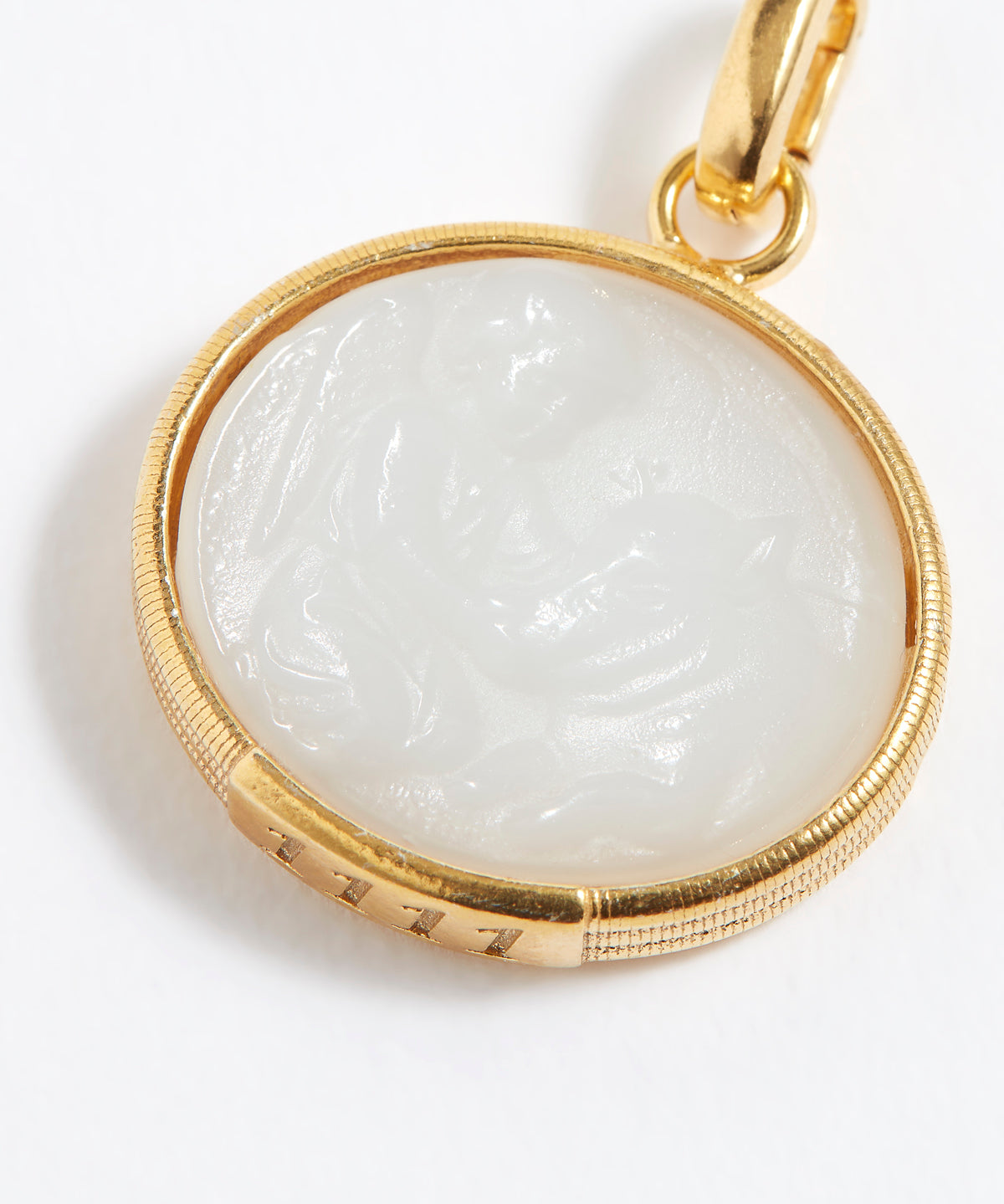 Gold pendant with a white stone on a white background