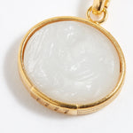 Gold pendant with a white stone on a white background