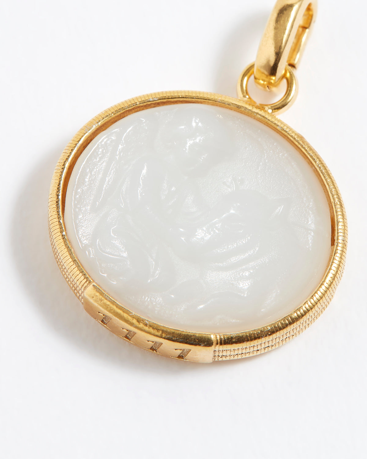 Gold pendant with a white stone on a white background