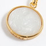 Gold pendant with a white stone on a white background