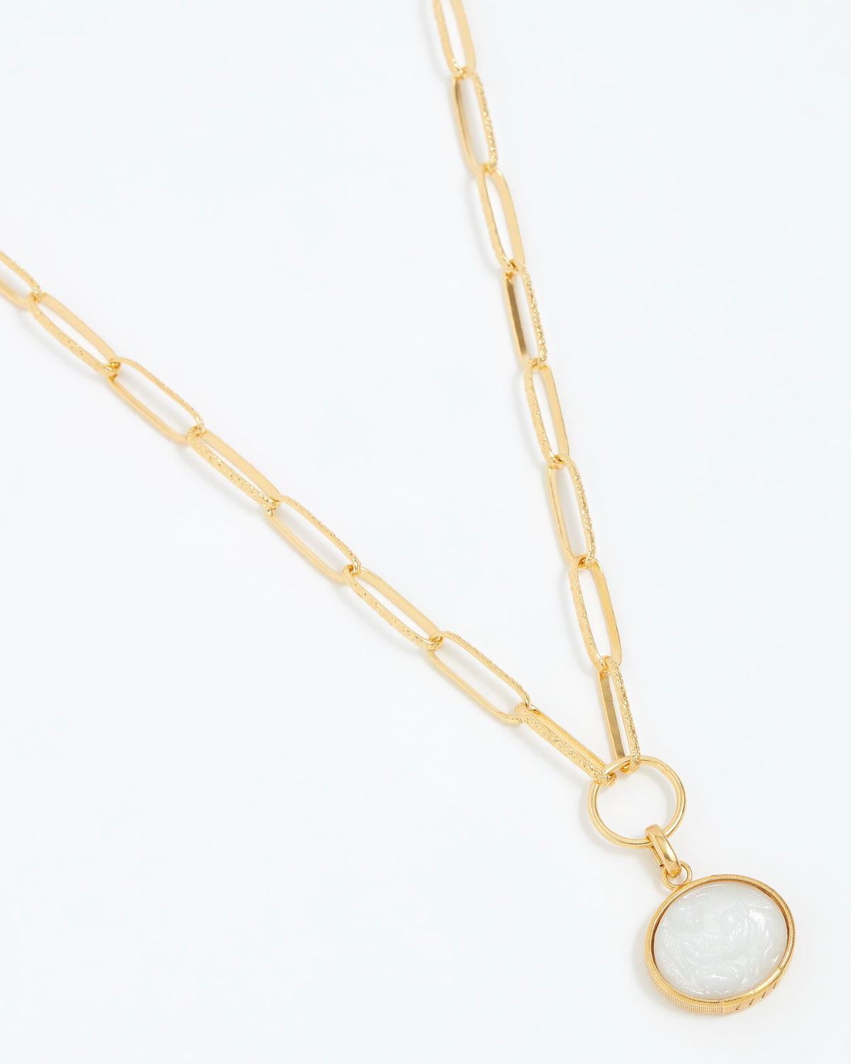Gold necklace with a white pendant on a white background