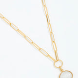 Gold necklace with a white pendant on a white background