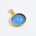 Gold pendant with blue stone on a white background