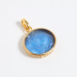 Gold pendant with blue stone on a white background